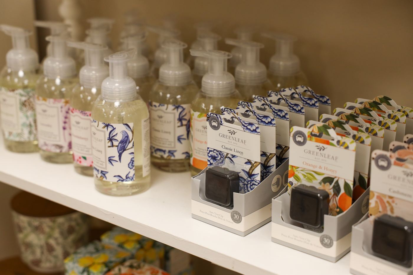 Glass foaming hand soap bottles and boxed bath gifts on a shelf