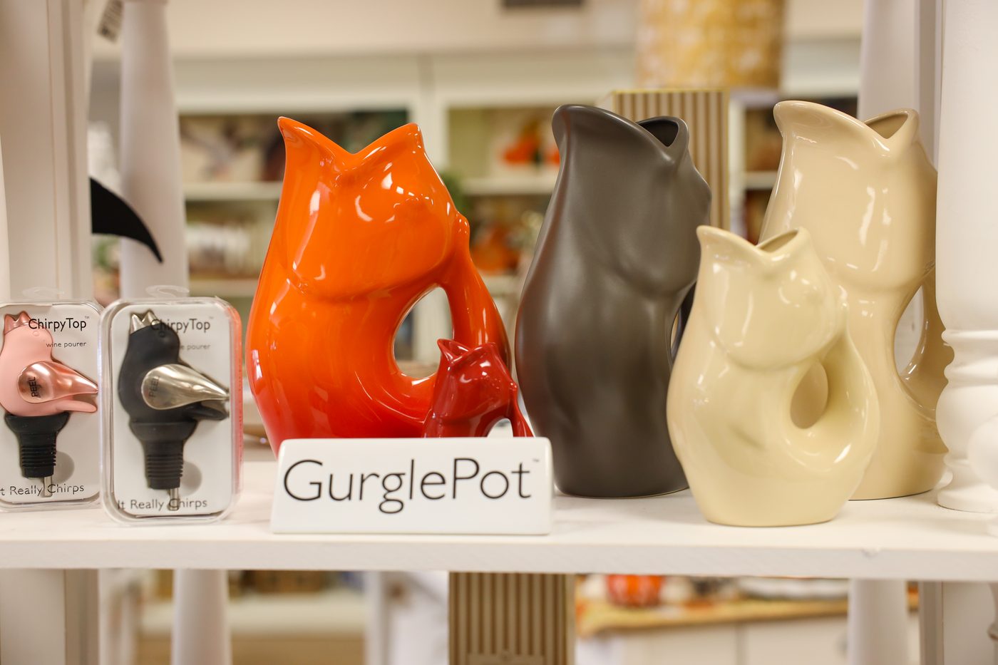 GurglePot fish pitchers in orange, brown, and cream on a shop shelf