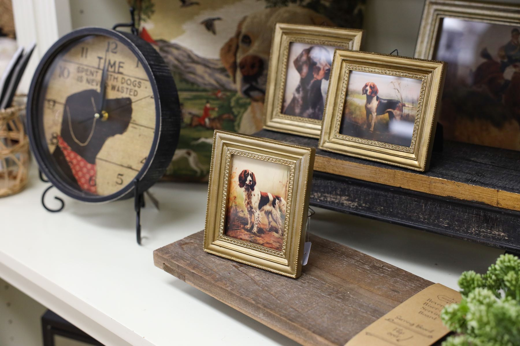 Gilded frames with spaniel portraits and a dog clock on a wooden display