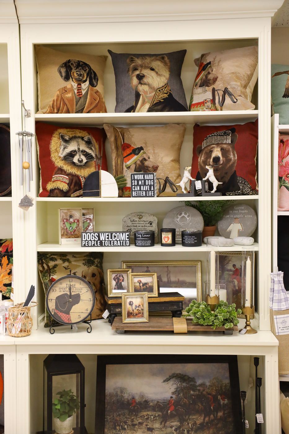 A tall shelf of pillows with dogs, a raccoon, and a bear dressed in period clothing