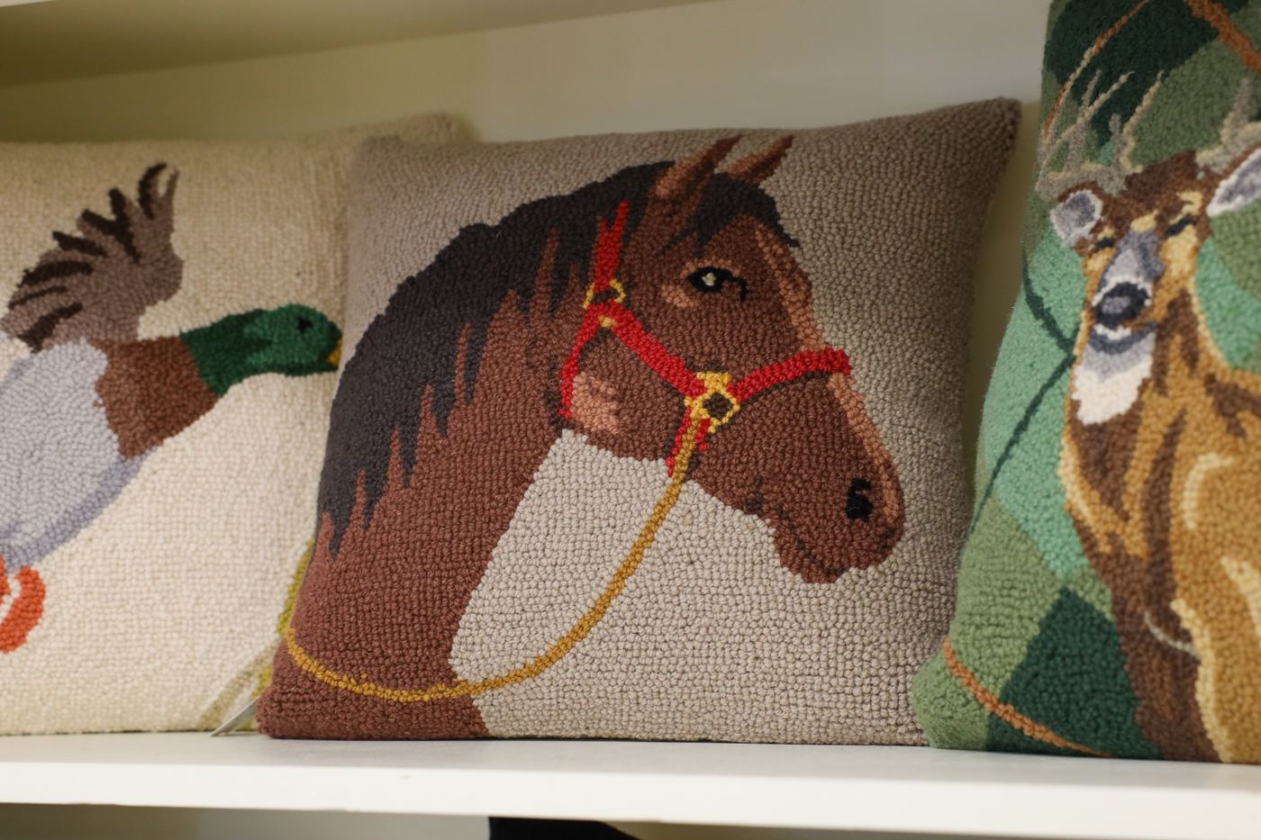 Hooked wool pillows of a mallard duck, a horse, and a deer
