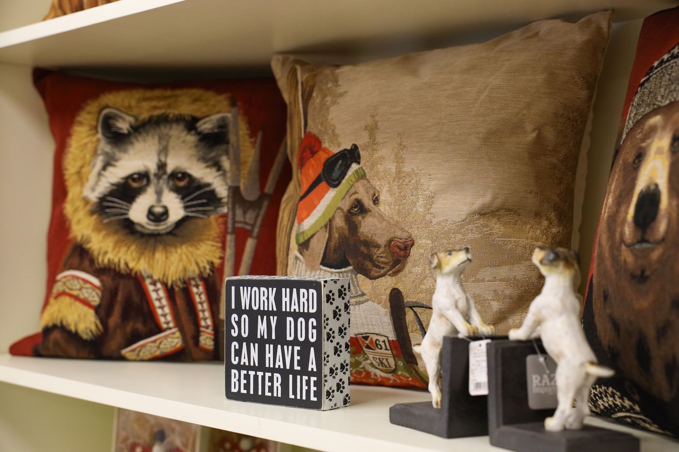 Portrait pillows of a raccoon and a hound beside dog figurines and a sign