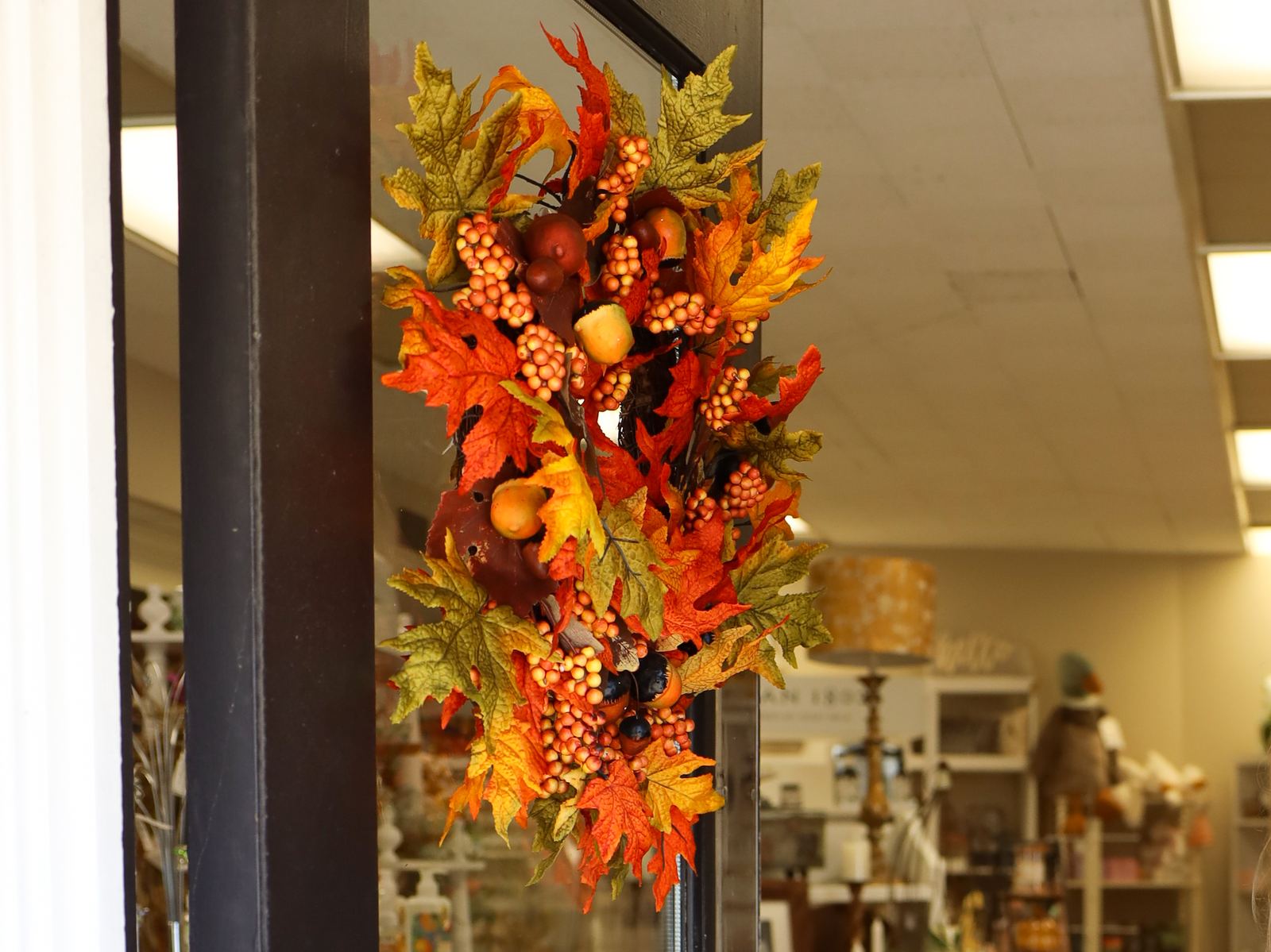 An autumn wreath of orange leaves and berries hanging on the front door of The Finishing Touch Store