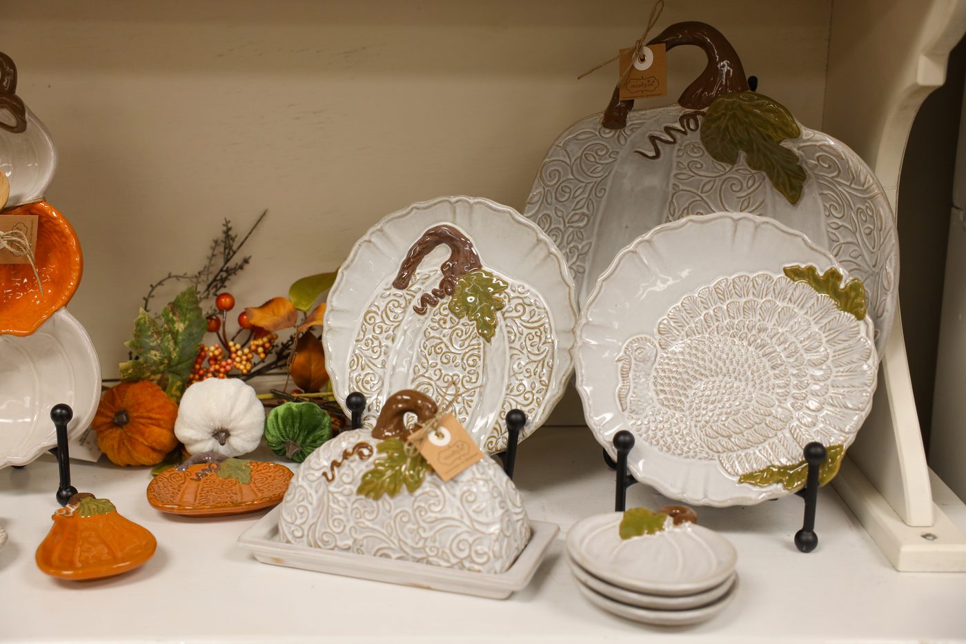 White pumpkin plates, a pumpkin butter dish, and harvest accents on a shop shelf