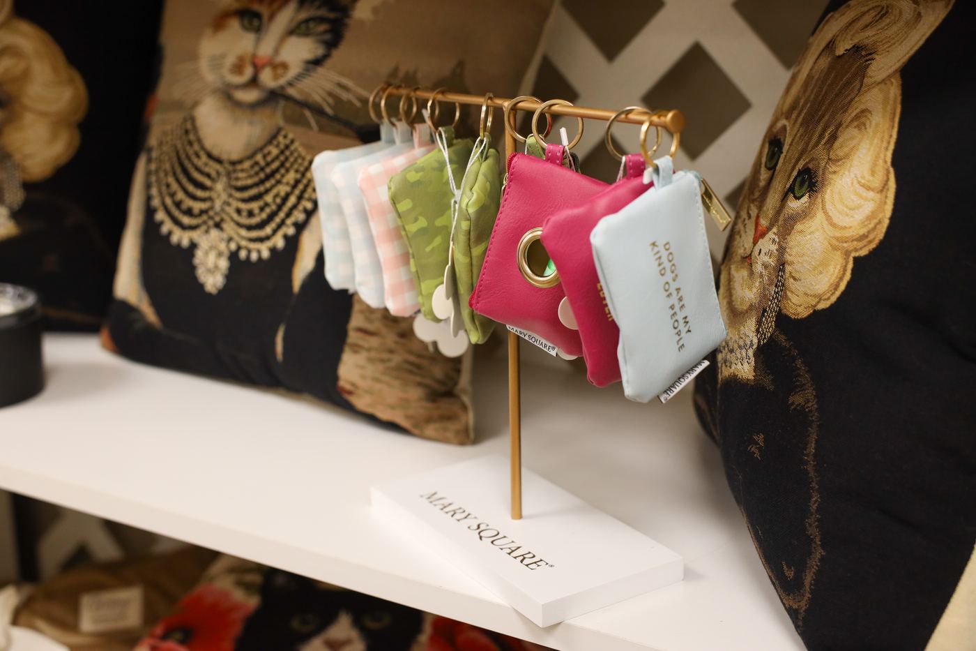Small zip pouches in soft colors on a gold display stand