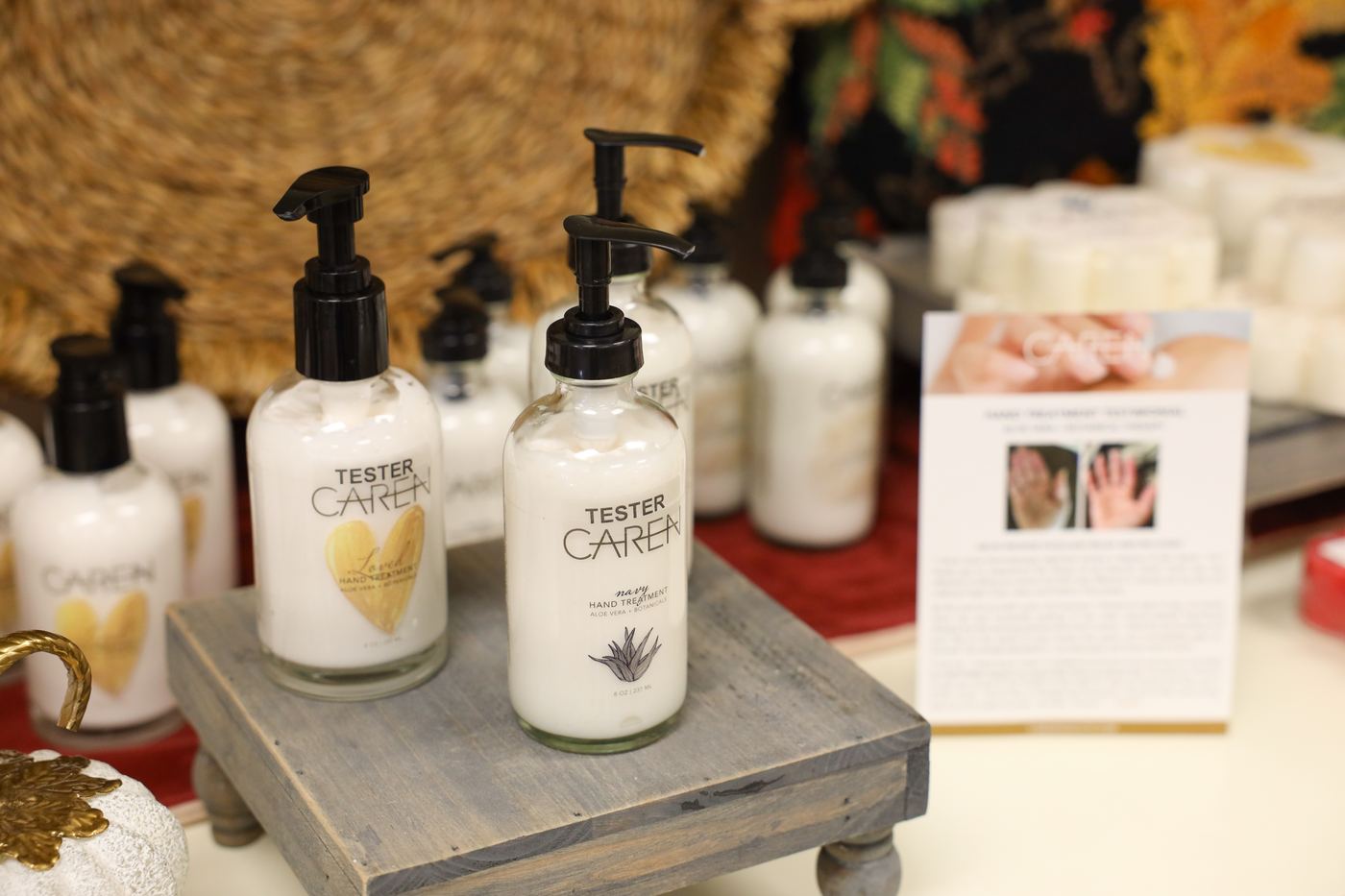 Caren hand lotions, one with a heart on the label, on a wooden riser