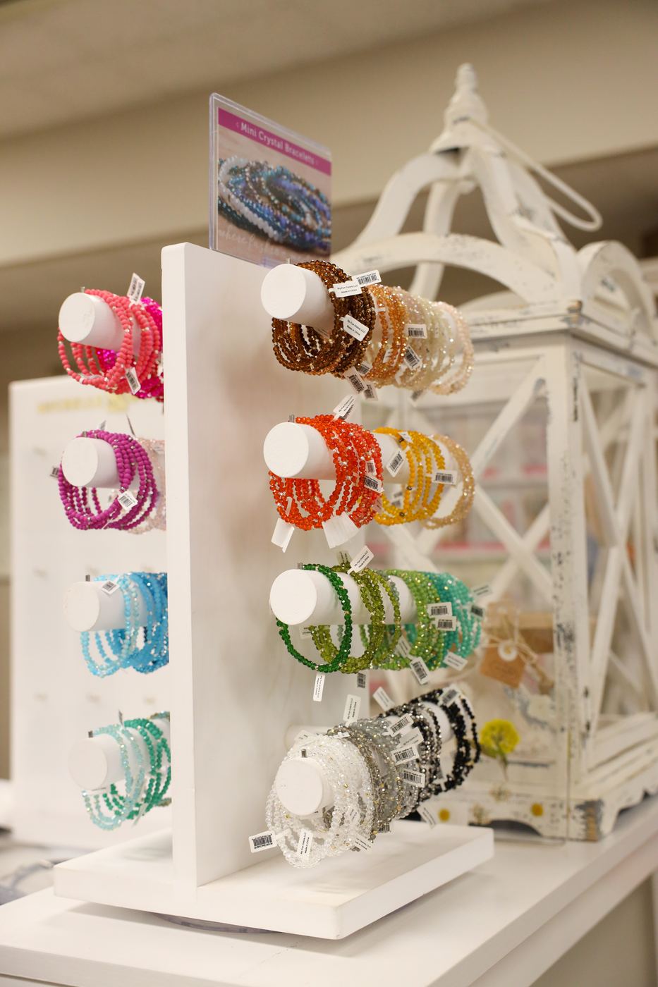 Colorful bracelets stacked on a white jewelry stand